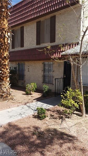 rear view of house with a tiled roof and stucco siding