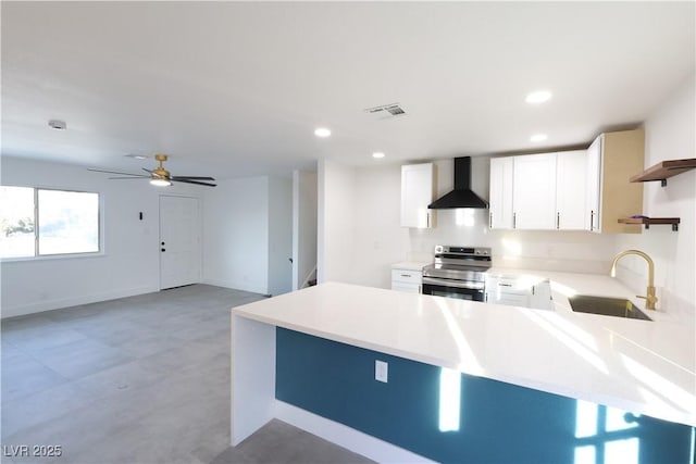 kitchen with wall chimney exhaust hood, a peninsula, stainless steel electric range, light countertops, and a sink