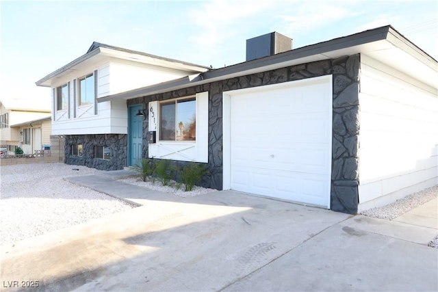 view of front of house with cooling unit, stone siding, an attached garage, and concrete driveway