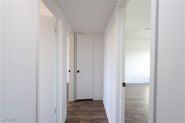 corridor featuring dark wood finished floors and baseboards