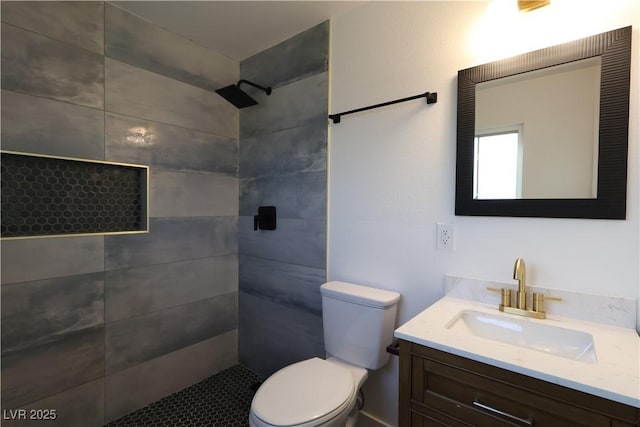 bathroom featuring tiled shower, vanity, and toilet