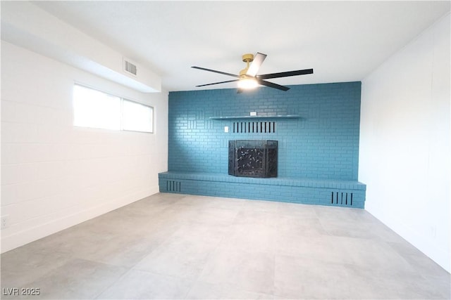 empty room featuring a ceiling fan, a brick fireplace, and visible vents