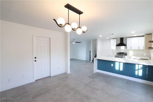 kitchen featuring white cabinets, stainless steel electric range oven, light countertops, wall chimney range hood, and a sink