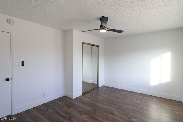 unfurnished bedroom featuring a textured ceiling, a closet, baseboards, and dark wood-style flooring