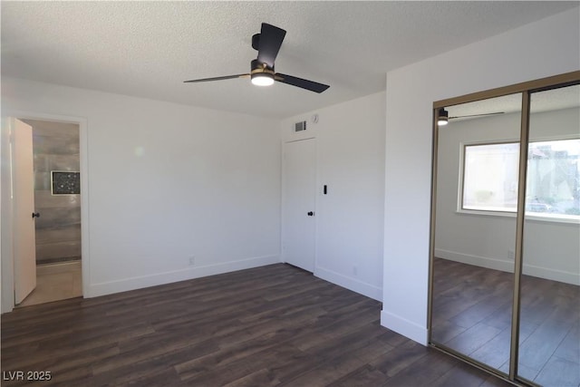 unfurnished bedroom with a textured ceiling, dark wood-type flooring, visible vents, baseboards, and a closet