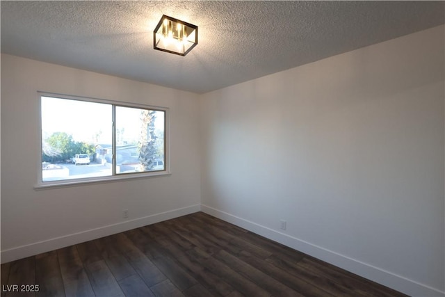 empty room with a textured ceiling, baseboards, and dark wood-type flooring