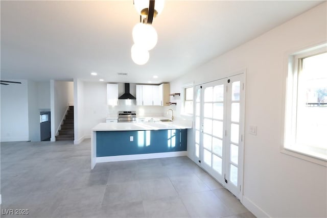 kitchen with a sink, white cabinets, electric stove, light countertops, and wall chimney exhaust hood