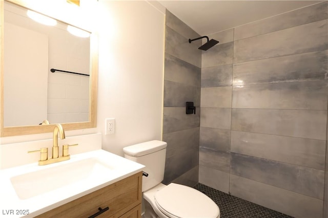 full bathroom featuring toilet, a tile shower, and vanity