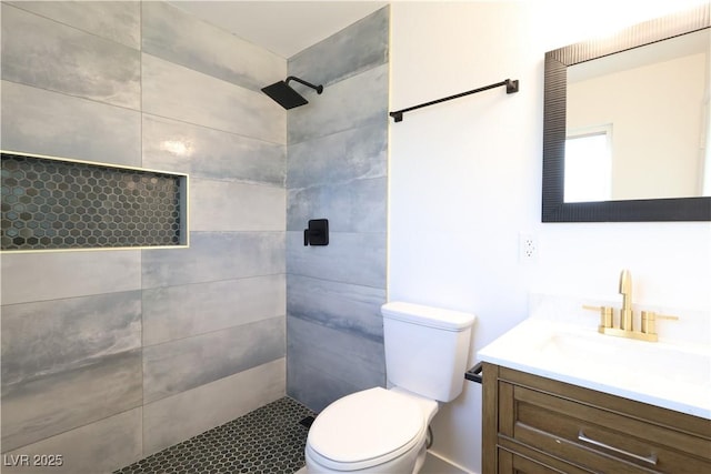 full bathroom featuring toilet, tiled shower, and vanity