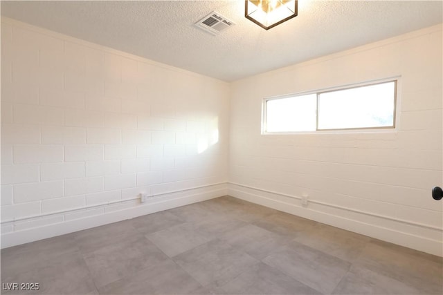 unfurnished room with a textured ceiling, visible vents, and tile patterned floors