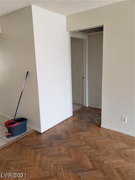 spare room with a textured ceiling, visible vents, and baseboards