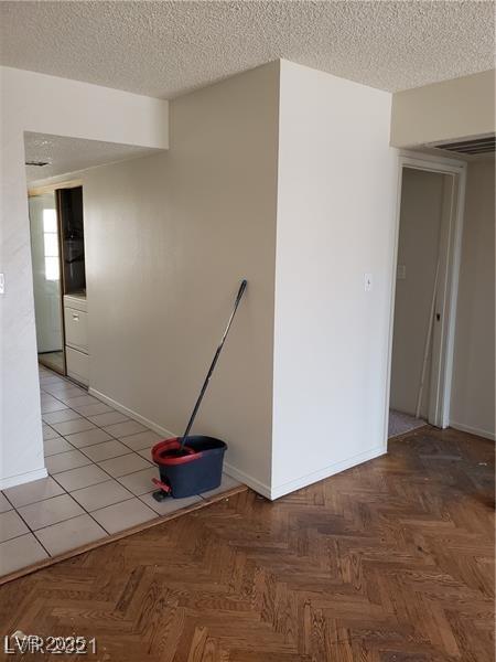 empty room with baseboards, visible vents, and a textured ceiling