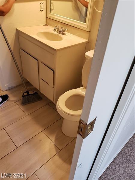 half bathroom with tile patterned flooring, vanity, and toilet