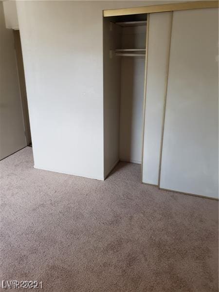 unfurnished bedroom featuring a closet and light colored carpet