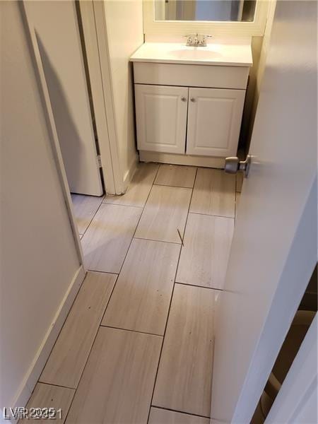 bathroom featuring wood finish floors, vanity, and baseboards