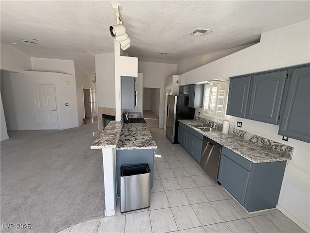 kitchen with lofted ceiling, light stone countertops, appliances with stainless steel finishes, and visible vents