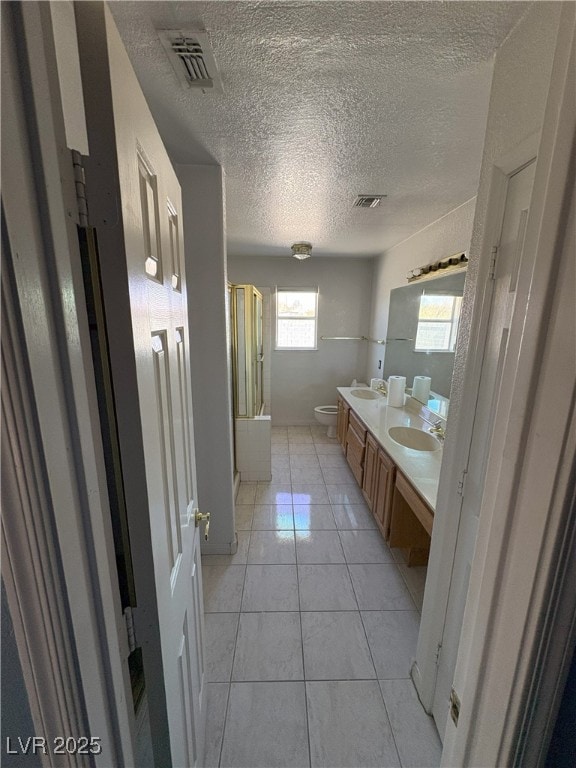 full bath featuring toilet, a sink, visible vents, and tile patterned floors