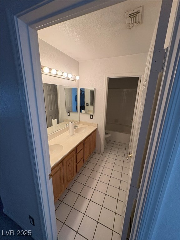 full bath with a textured ceiling, tile patterned flooring, toilet, visible vents, and double vanity