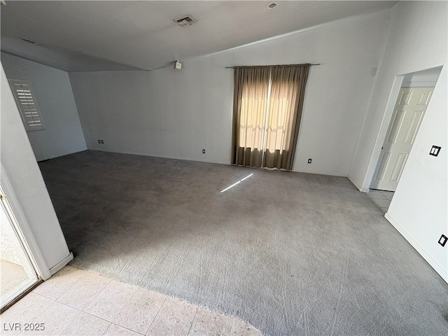 carpeted spare room featuring vaulted ceiling and visible vents