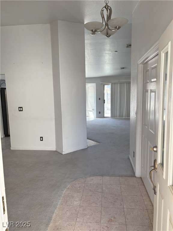 interior space featuring visible vents, baseboards, an inviting chandelier, tile patterned flooring, and carpet floors