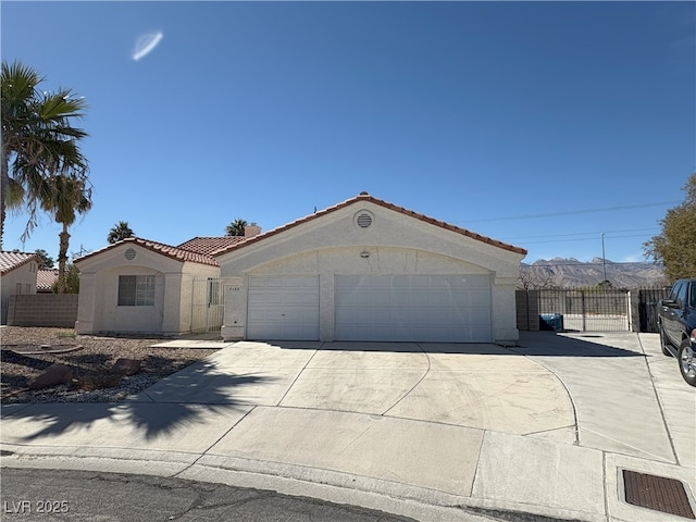 mediterranean / spanish house featuring an outbuilding, fence, a tiled roof, driveway, and stucco siding