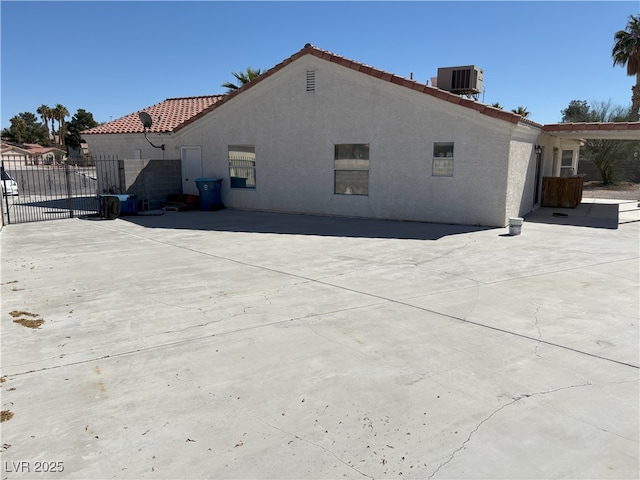 view of home's exterior with a gate, fence, cooling unit, and stucco siding