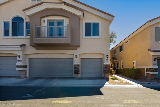 multi unit property with stucco siding, a tile roof, an attached garage, and a balcony