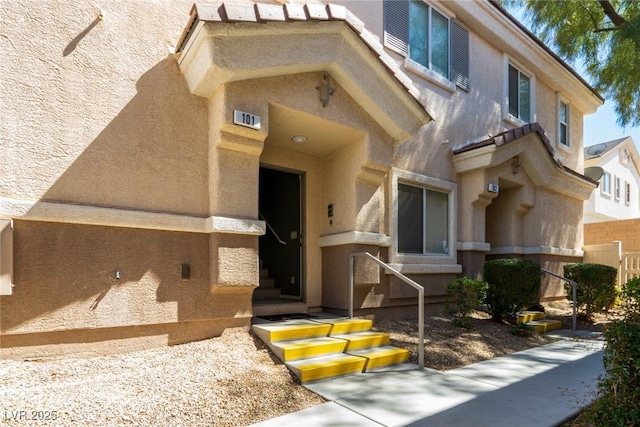 view of exterior entry featuring visible vents and stucco siding