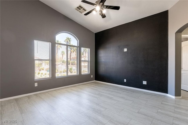 unfurnished room with baseboards, an accent wall, arched walkways, visible vents, and a ceiling fan