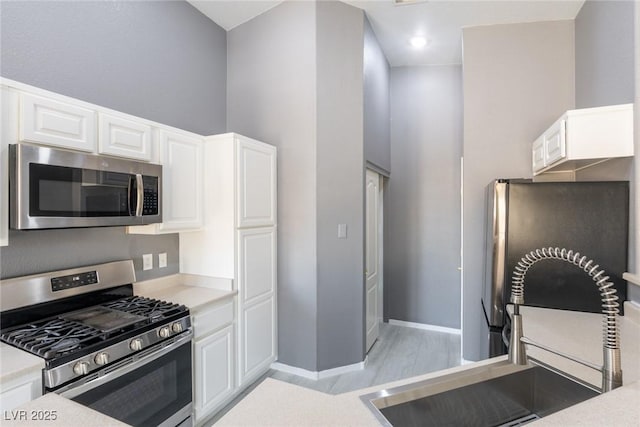 kitchen featuring light countertops, white cabinets, a sink, and appliances with stainless steel finishes