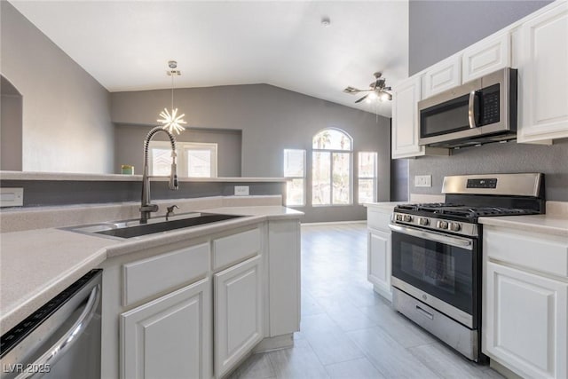 kitchen with white cabinetry, light countertops, lofted ceiling, a sink, and appliances with stainless steel finishes