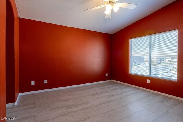 empty room with a ceiling fan, baseboards, and vaulted ceiling