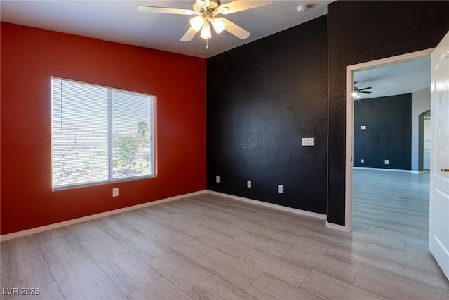 empty room featuring arched walkways, baseboards, and ceiling fan