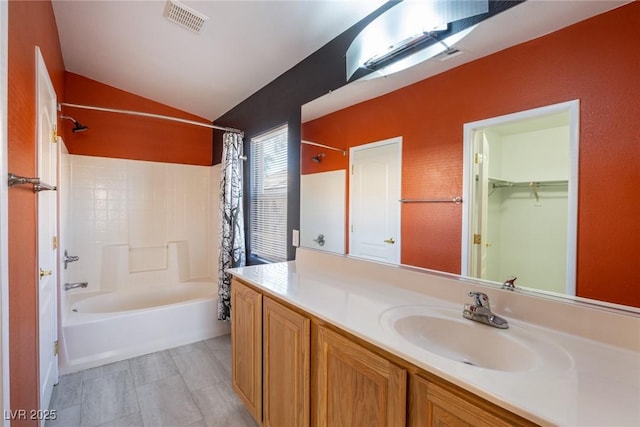 bathroom with visible vents, vanity, lofted ceiling, shower / bath combination with curtain, and a spacious closet