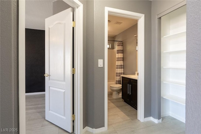 corridor with built in features, baseboards, and visible vents