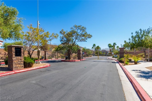 view of street featuring sidewalks, a gated entry, a gate, and curbs