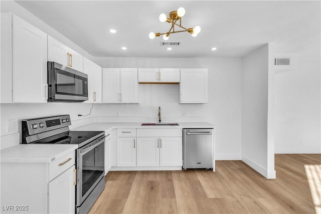 kitchen with light wood-style flooring, visible vents, stainless steel appliances, and a sink