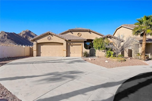 mediterranean / spanish-style home with driveway, an attached garage, a gate, fence, and stucco siding