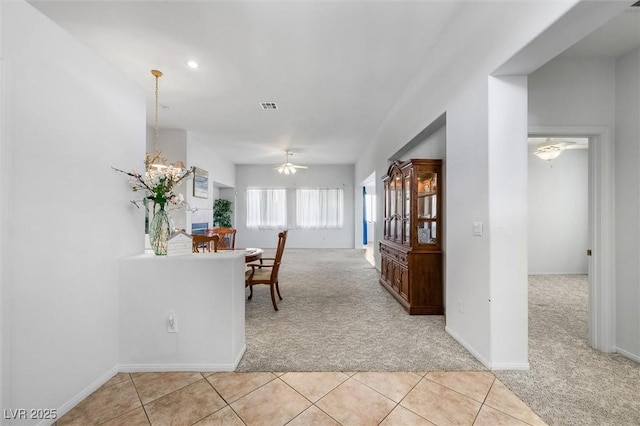 dining room with light carpet, ceiling fan with notable chandelier, light tile patterned flooring, and visible vents