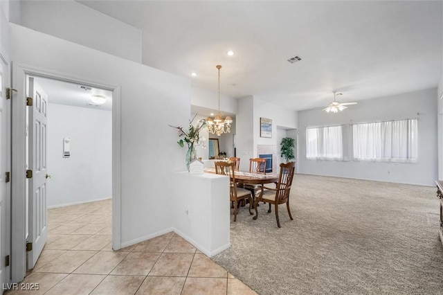 dining space with light tile patterned floors, visible vents, light carpet, baseboards, and ceiling fan with notable chandelier