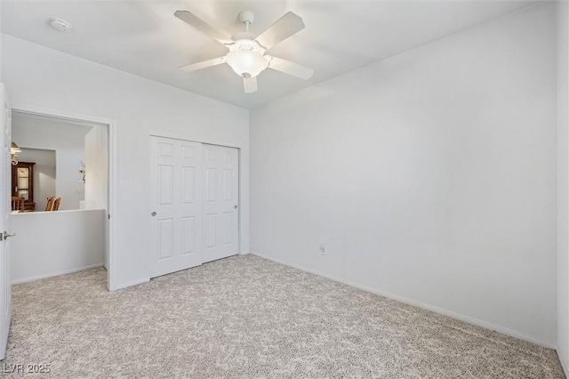 unfurnished bedroom with carpet floors, a closet, baseboards, and a ceiling fan