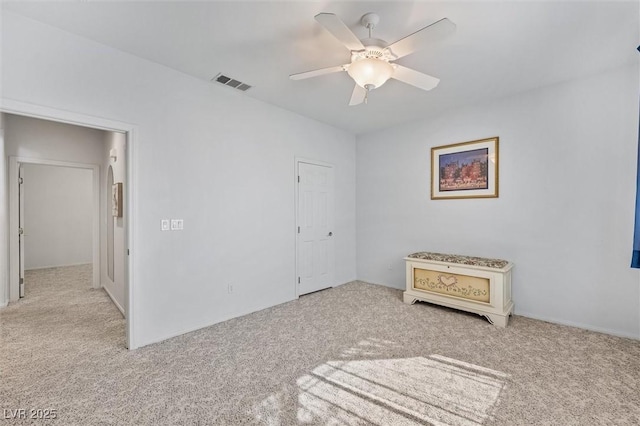 unfurnished room with carpet, visible vents, and ceiling fan