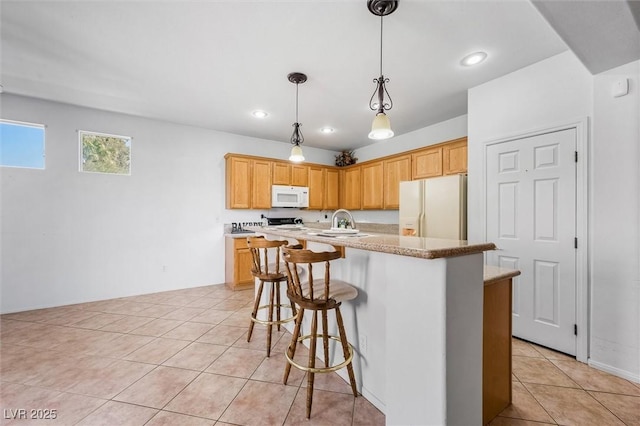 kitchen featuring light tile patterned floors, decorative light fixtures, white appliances, a breakfast bar, and a center island with sink