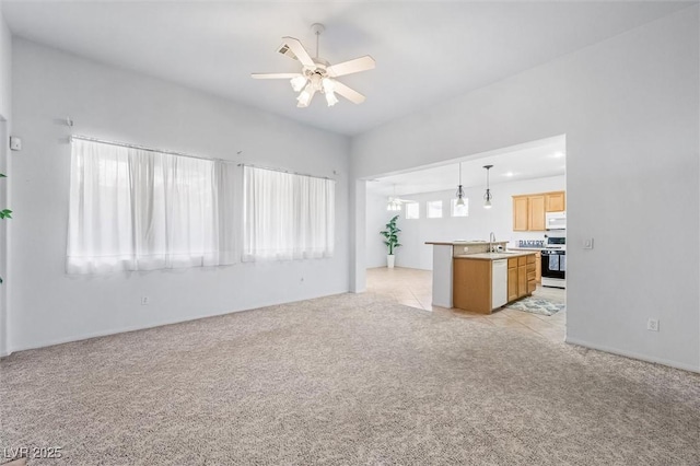 unfurnished living room featuring a sink, a ceiling fan, and light colored carpet