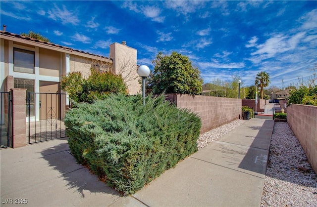 view of side of home featuring a gate, fence, and stucco siding