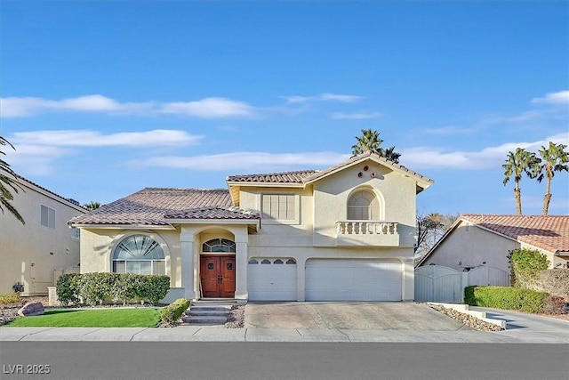 mediterranean / spanish-style house featuring a tile roof, concrete driveway, stucco siding, an attached garage, and a gate