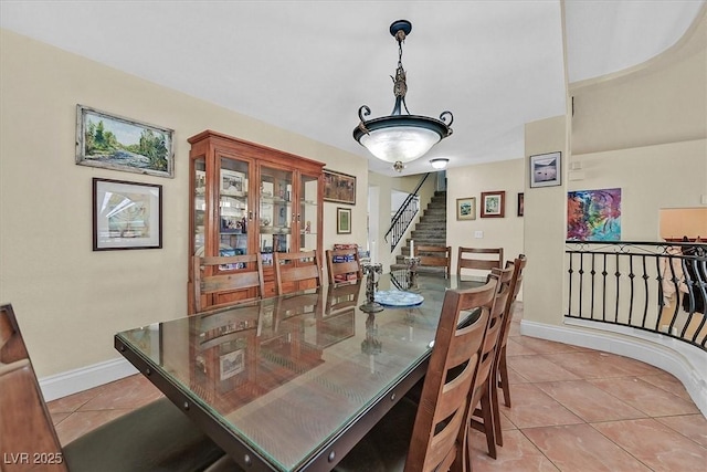 dining room featuring light tile patterned floors, stairway, and baseboards