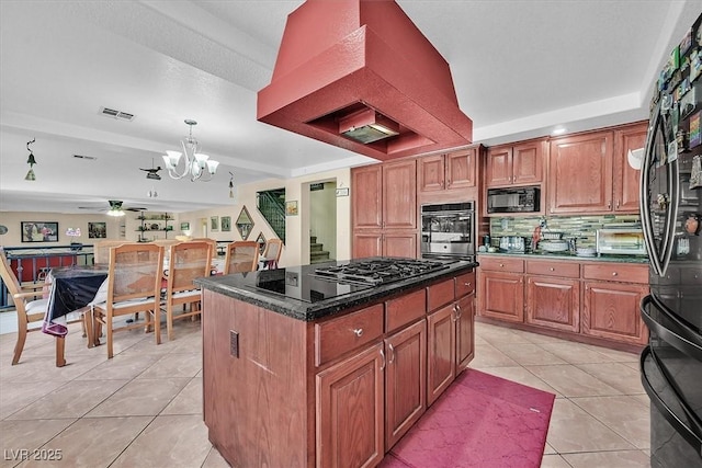 kitchen featuring visible vents, a kitchen island, decorative light fixtures, light tile patterned floors, and black appliances