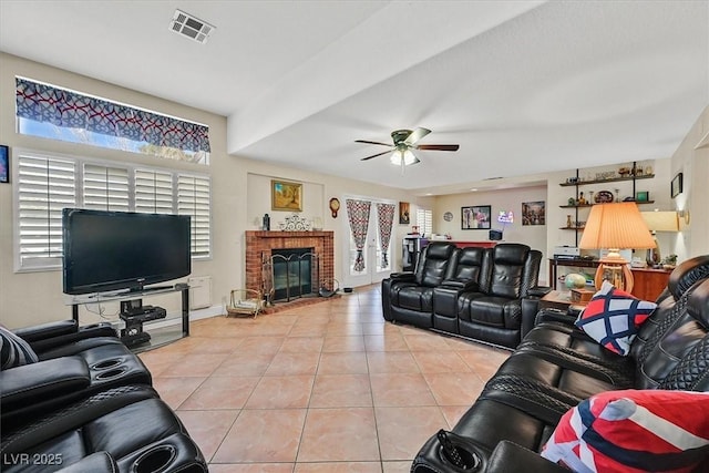 living area featuring light tile patterned floors, visible vents, a ceiling fan, and a fireplace