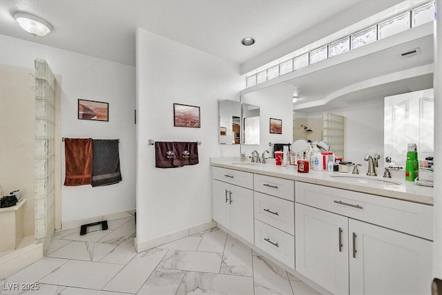 bathroom featuring baseboards, marble finish floor, a tile shower, and a sink